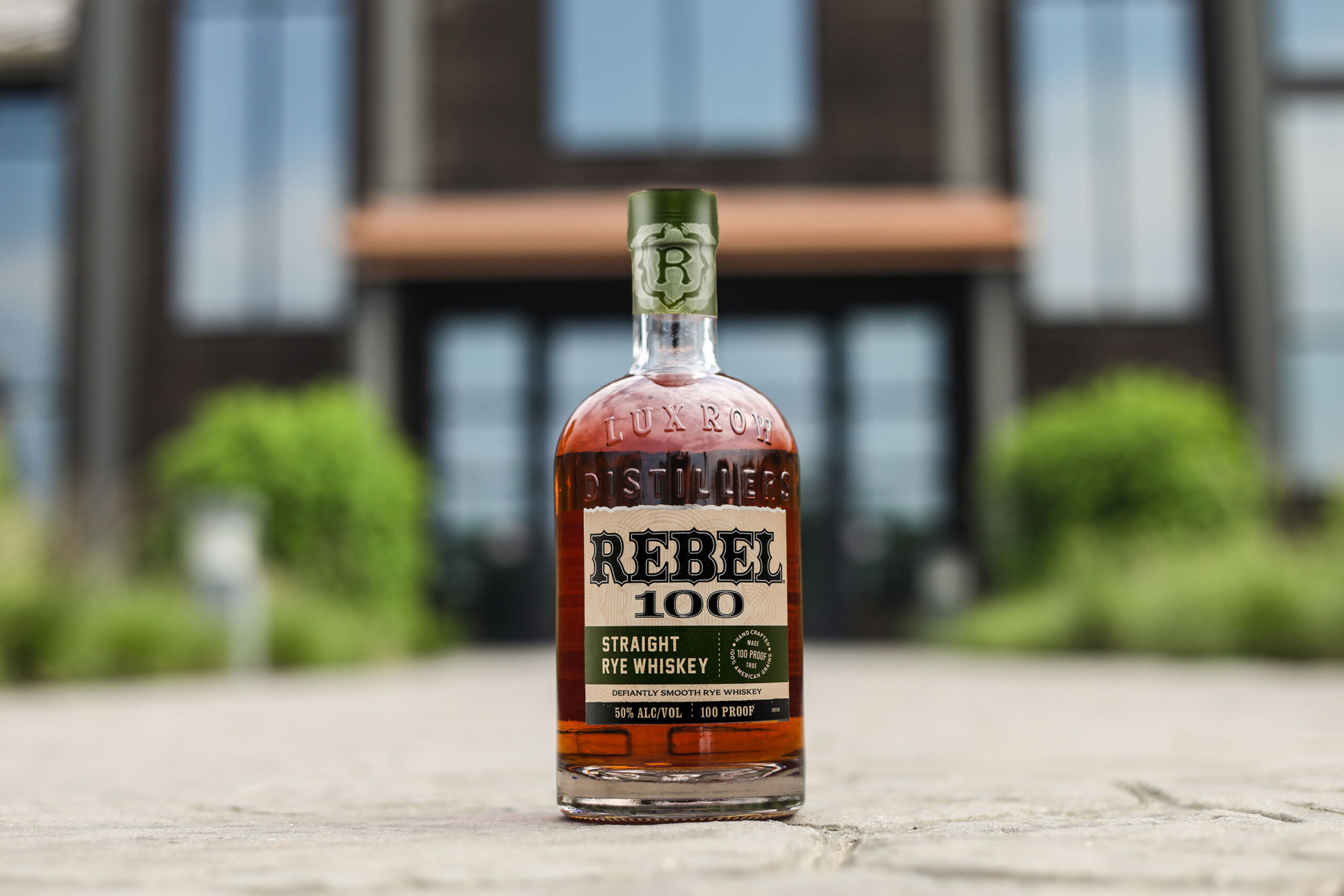 A bottle of Rebel 100 Rye in front of Lux Row Distillers